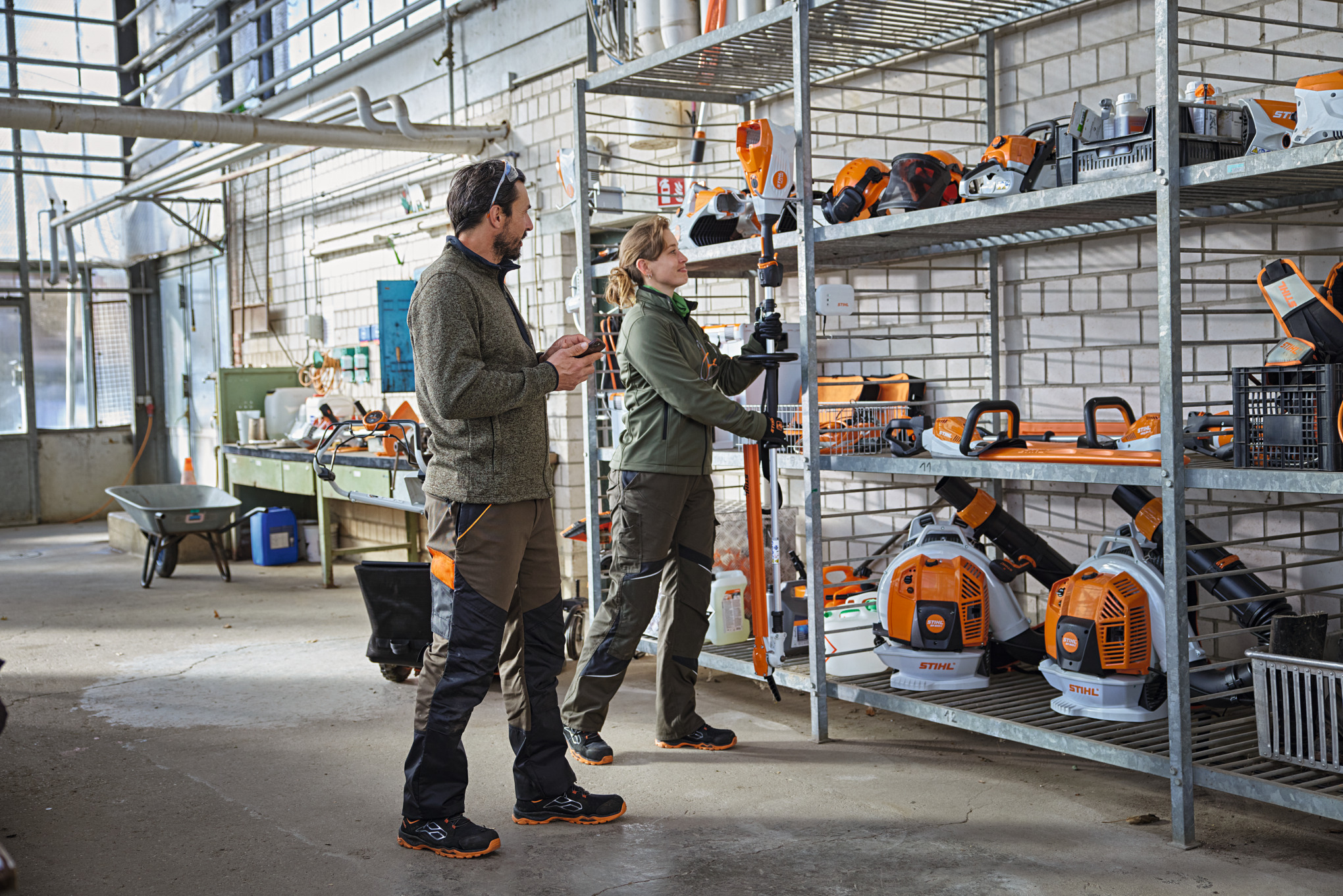 Profesionales de jardinería y paisajismo en un almacén revisando el estado del producto mediante la aplicación STIHL connected.