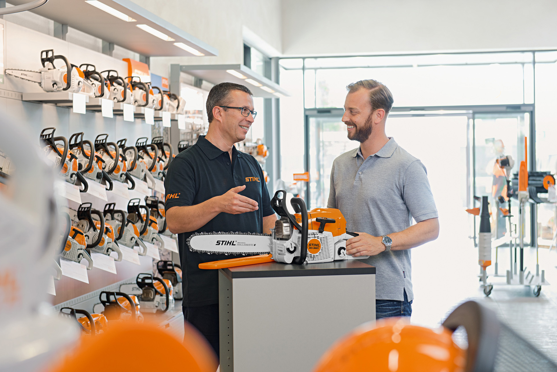 Un distribuidor STIHL aconseja a un hombre joven durante la compra de una motosierra STIHL