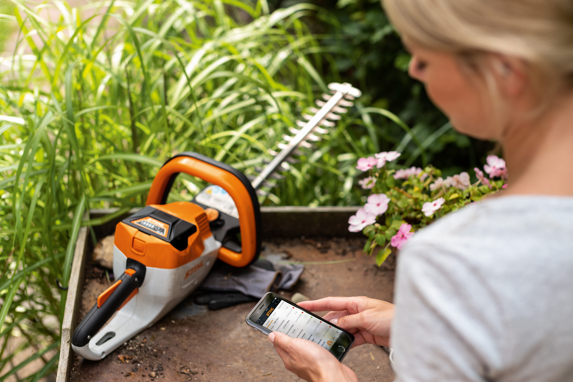 Una mujer registra su cortasetos STIHL con la aplicación STIHL en un smartphone